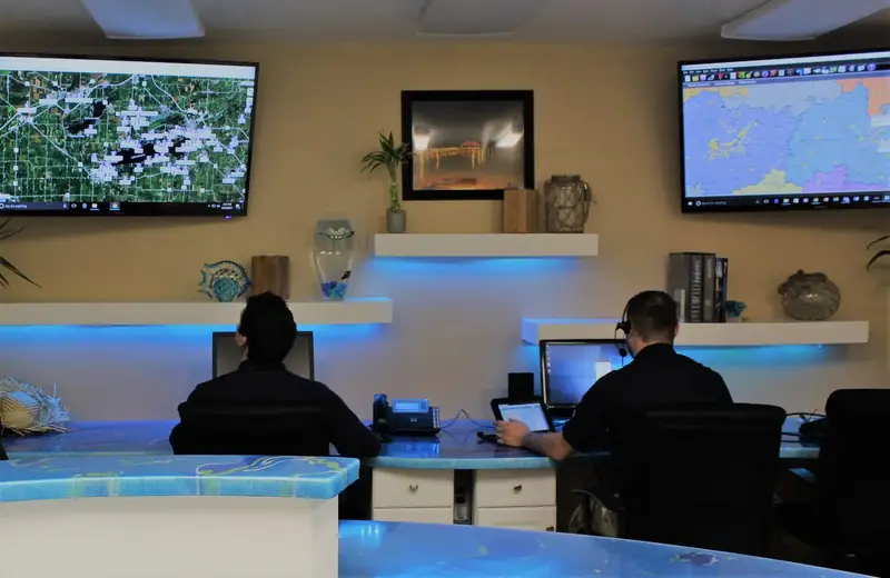 Poolblu Call Center staff wearing headsets at a dispatch desk with service-territory maps on wall screens.