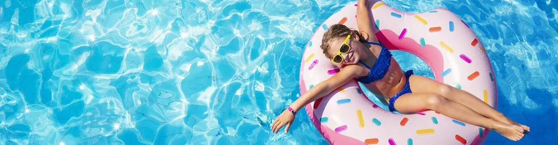 Overhead view of a girl relaxing on a donut float in clear blue pool water.